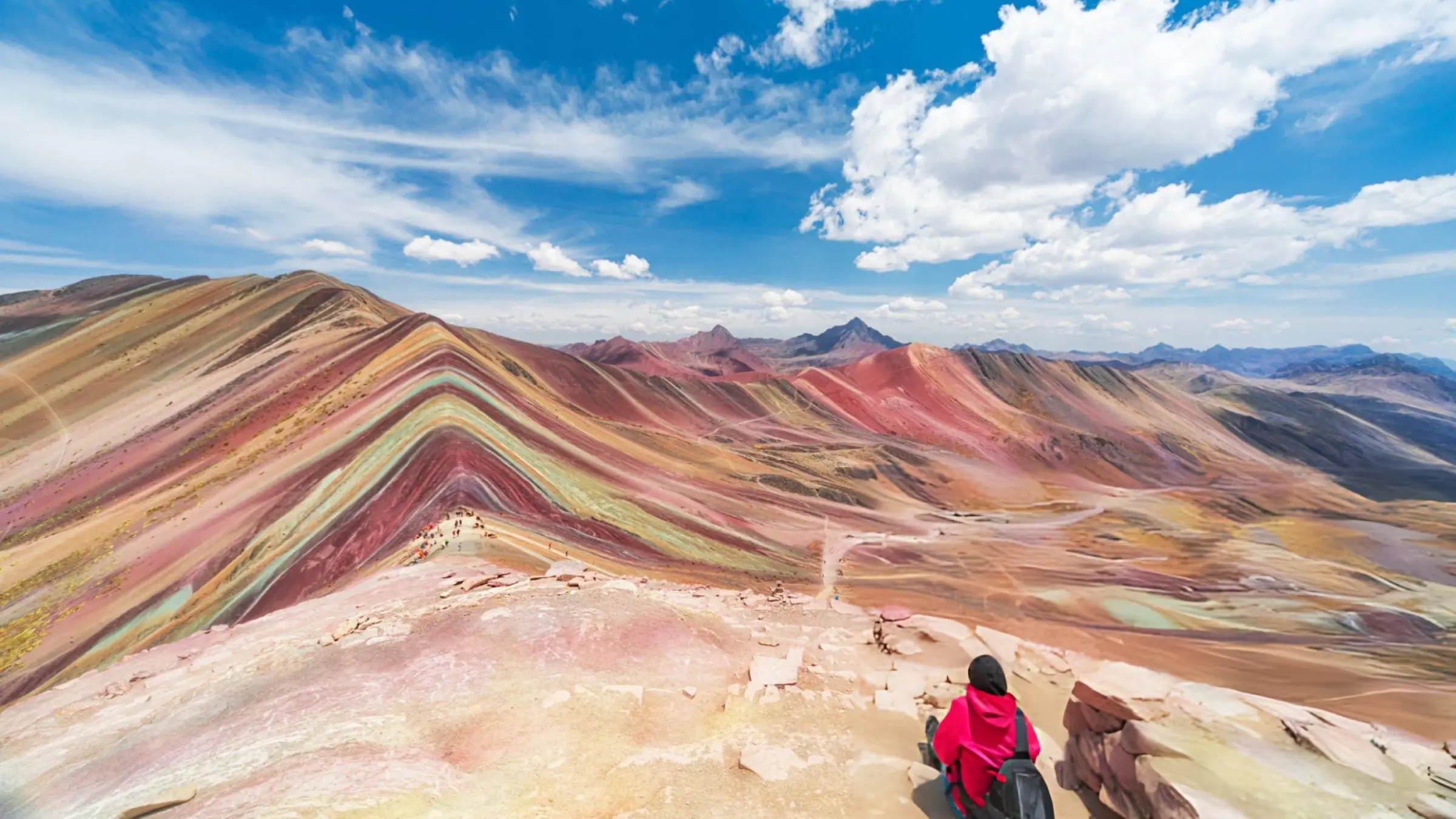 Traveler overlooking Rainbow Mountain Vinicunca and its colorful mineral stripes near Cusco, Peru.